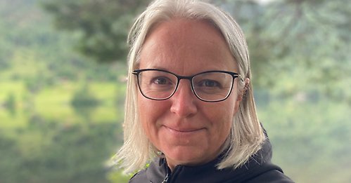 Anna Perman ler, står framför en sjö och träd